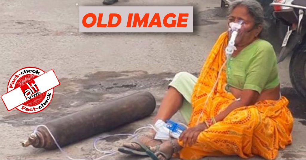 ऑक्सीजन सिलिंडर के साथ सड़क पर बैठी महिला की तस्वीर कोरोनाकाल से पहले की है